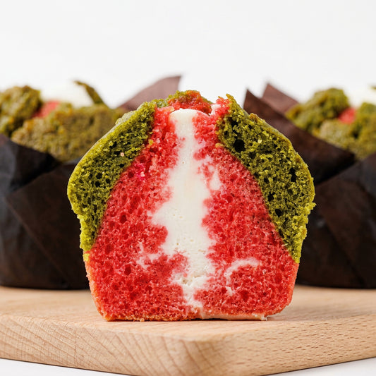 A sliced strawberry matcha cream cheese filling muffin, displayed on a wooden board.