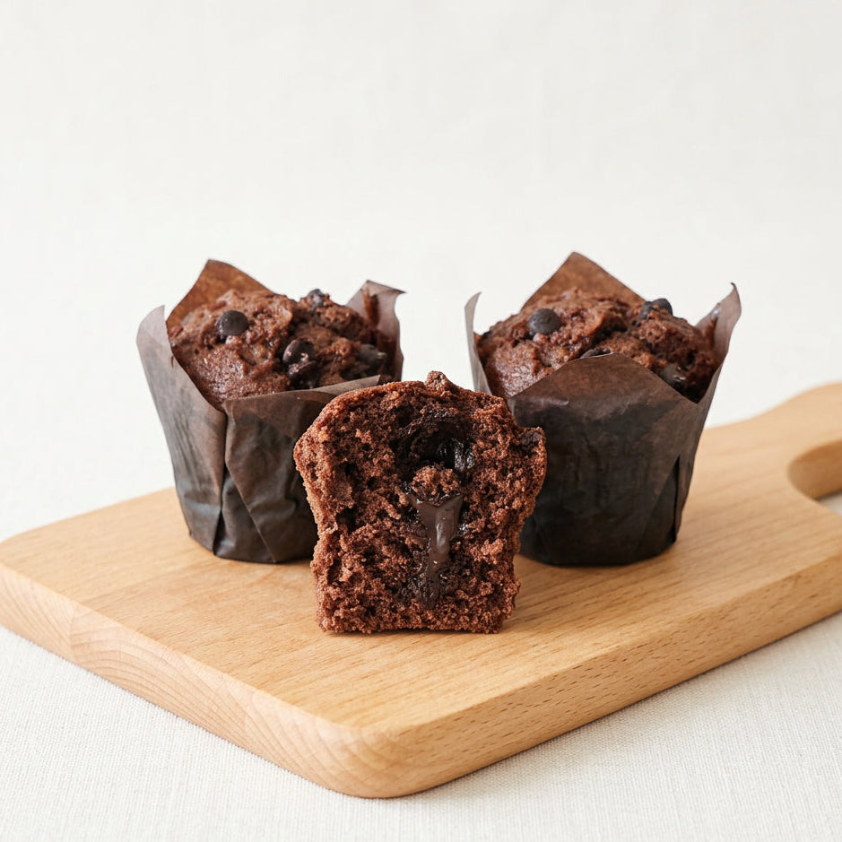 Three chocolate muffins with chocolate filling on a wooden board