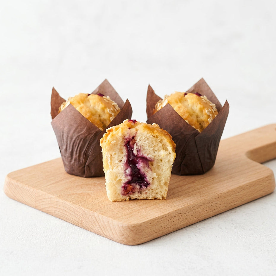 Mini Muffins Blueberry with brown paper liners on a wooden board