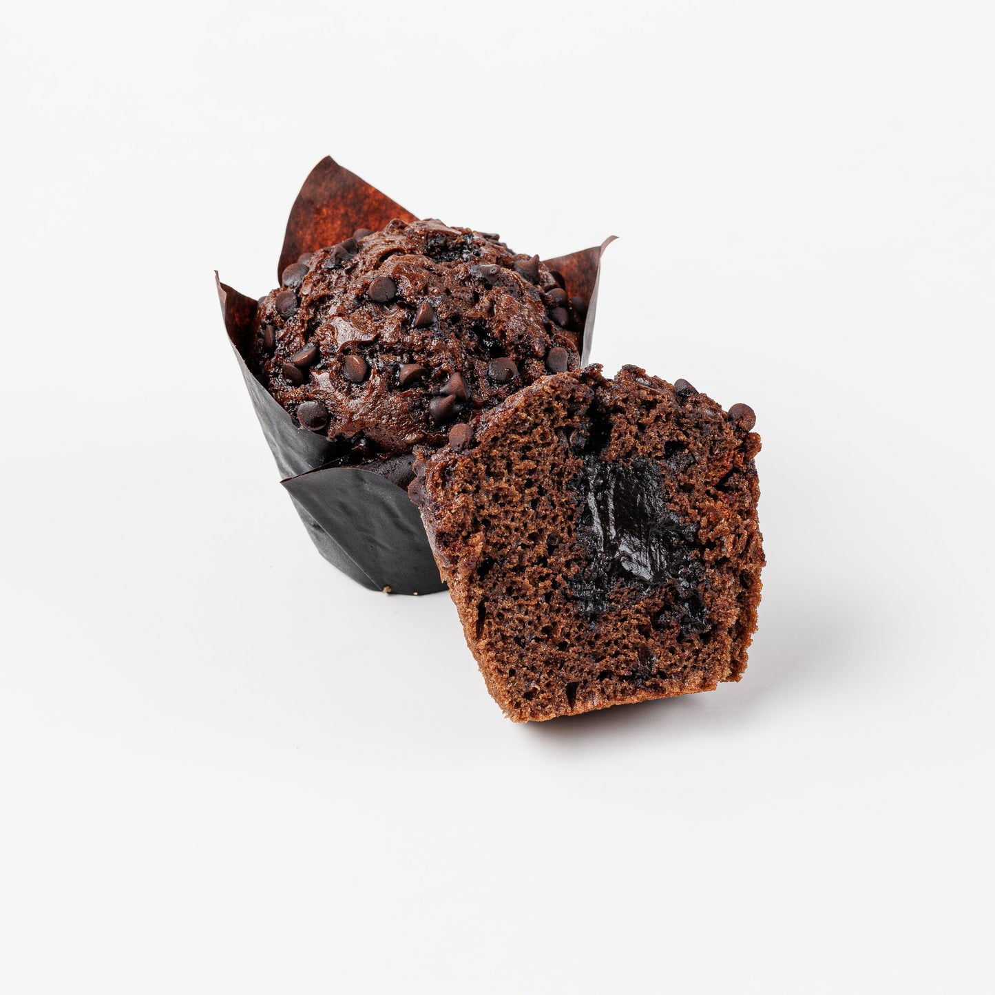 Chocolate muffin with molten filling cut in half on a white background
